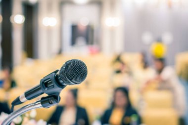 Microphone on stage in seminar room or speaking conference hall or educational seminar classroom with abstract blurred background. Selective focus on microphone. clipart