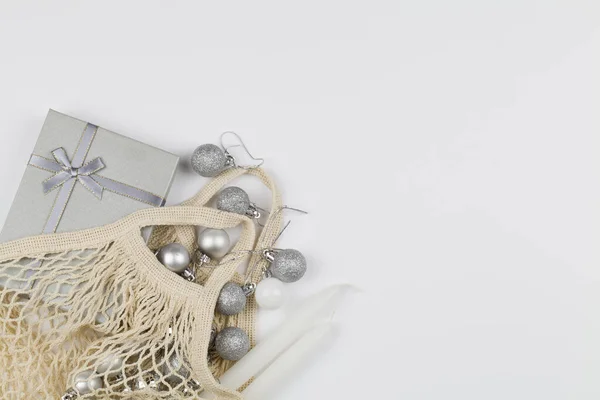 Рождественский праздник декоративные серые игрушки в экологически чистой торговой сетке мешок на белом фоне с копировальным пространством . — стоковое фото