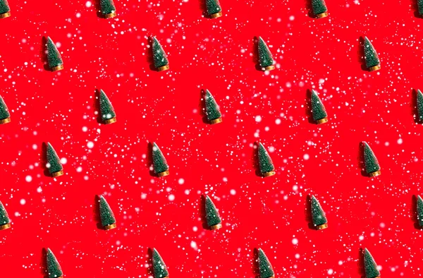 Minimální vzor pozadí zelených vánočních stromků na červeném pozadí se sněhem — Stock fotografie