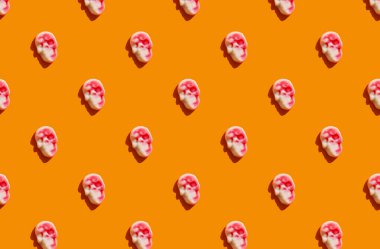 Parlak turuncu arka planda kafatası şeklinde marmelatla yapılmış güneş ışığı deseni. Komik tatil düzüşme konsepti.