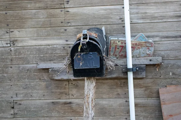 Frente de uma caixa de correio do país abandonado velho com ninho de pássaro dentro dele no lado de um galpão — Fotografia de Stock