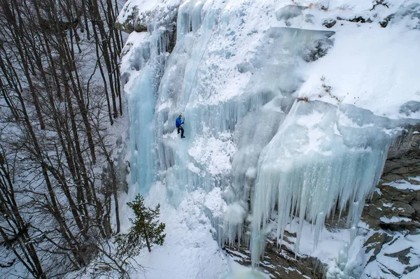 Ice climbing the North Greece, man climbing frozen waterfall.