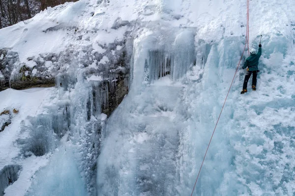 Ice climbing the North Greece, man climbing frozen waterfall.