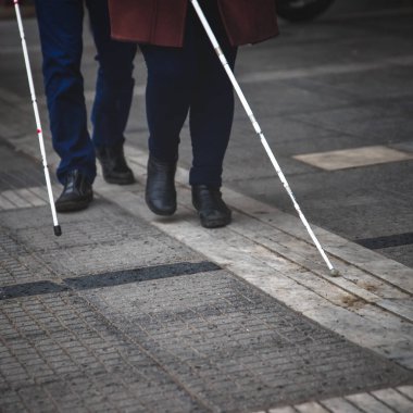 kör adam ve beyaz yürüyüş kullanarak sokakta yürüyen kadın 