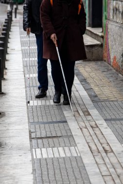 kör adam ve beyaz yürüyüş kullanarak sokakta yürüyen kadın 