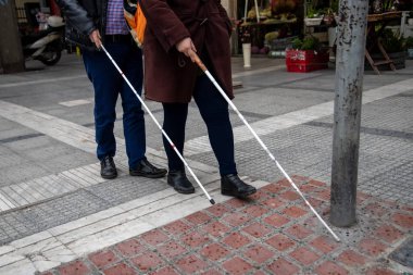 kör adam ve beyaz yürüyüş kullanarak sokakta yürüyen kadın 