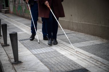 kör adam ve beyaz yürüyüş kullanarak sokakta yürüyen kadın 