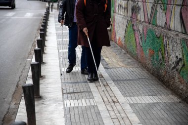 kör adam ve beyaz yürüyüş kullanarak sokakta yürüyen kadın 