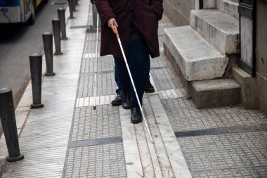 kör adam ve beyaz yürüyüş kullanarak sokakta yürüyen kadın 