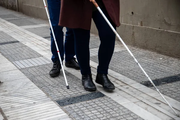 Slepý muž a žena chůze na ulici pomocí bílé chůzi — Stock fotografie