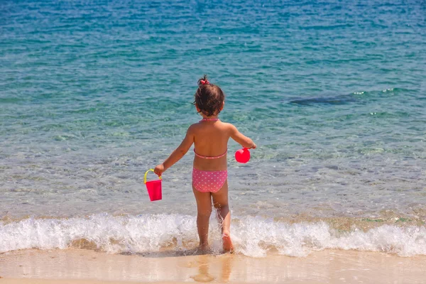 Πίσω όψη του ένα μικρό χαριτωμένο κορίτσι παίζει σε μια παραλία κοντά στο s — Φωτογραφία Αρχείου