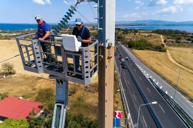 Elektrikçiler yüklemek ve repai elektrik direkleri üzerinde tırmanıyor