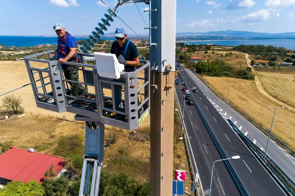 Les électriciens grimpent sur des poteaux électriques pour installer et repai — Photo