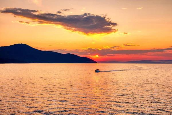 Boot naar de zee bij zonsondergang op de achtergrond van bergen en zon — Stockfoto