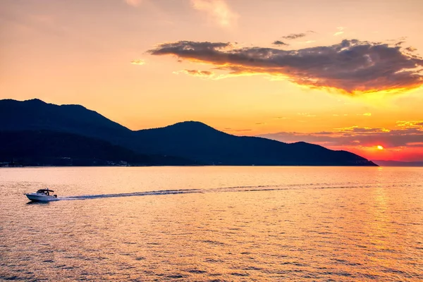 Boot naar de zee bij zonsondergang op de achtergrond van bergen en zon — Stockfoto
