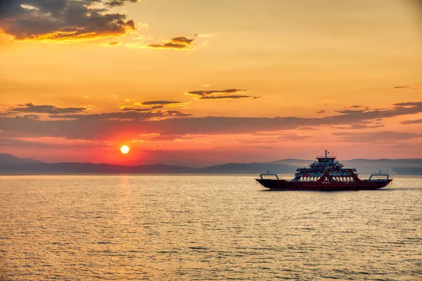 Veerboot naar de zee bij zonsondergang op de achtergrond van bergen a — Stockfoto