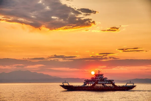 Veerboot naar de zee bij zonsondergang op de achtergrond van bergen a — Stockfoto