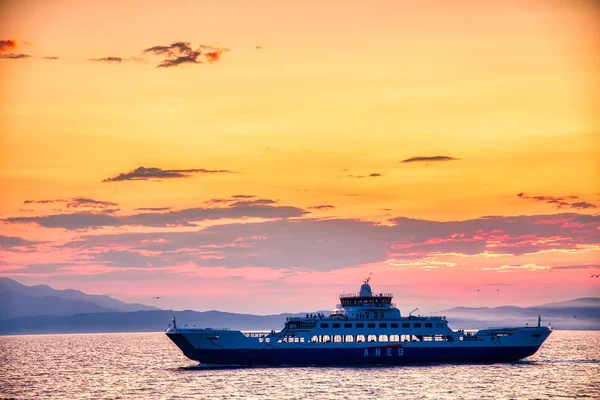Veerboot naar de zee bij zonsondergang op de achtergrond van bergen a — Stockfoto