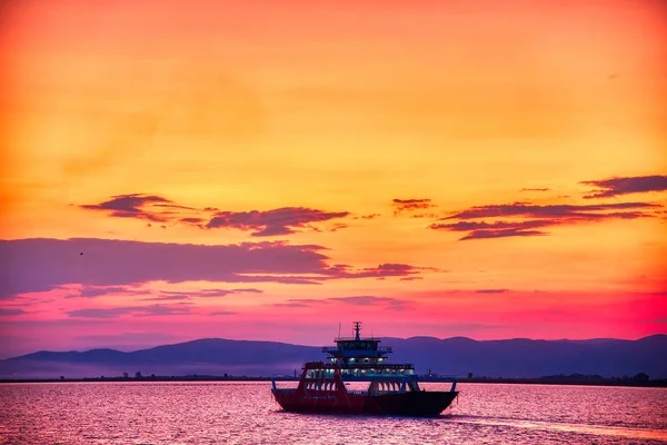 Veerboot naar de zee bij zonsondergang op de achtergrond van bergen a — Stockfoto