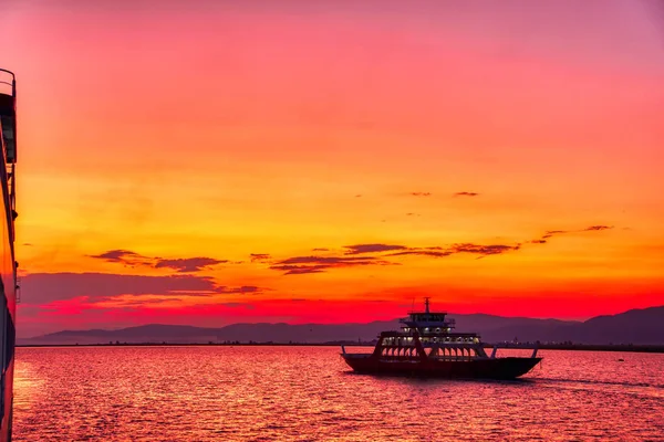 Veerboot naar de zee bij zonsondergang op de achtergrond van bergen a — Stockfoto