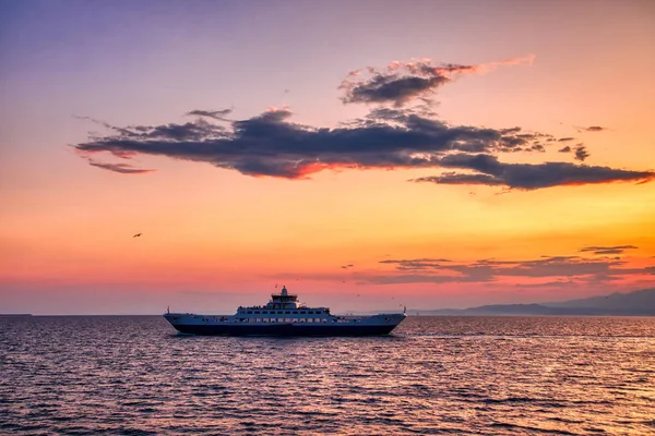 Färje båt till havet vid solnedgången i bakgrunden av bergen en — Stockfoto