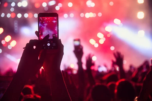 People taking photographs with touch smart phone during a music