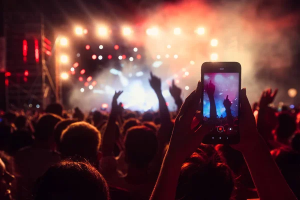 Personas que toman fotografías con un teléfono inteligente táctil durante una música — Foto de Stock