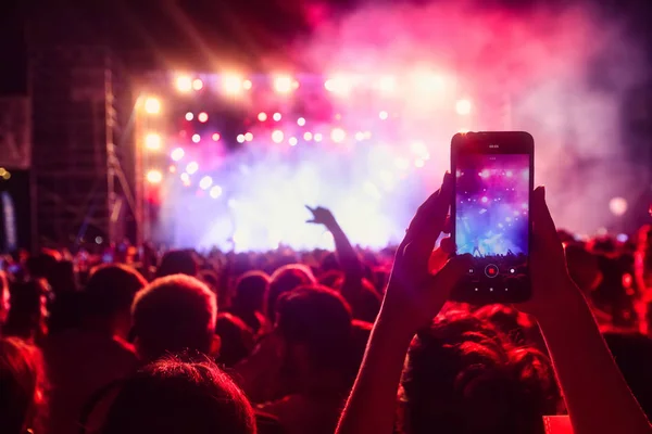 Personas que toman fotografías con un teléfono inteligente táctil durante una música — Foto de Stock