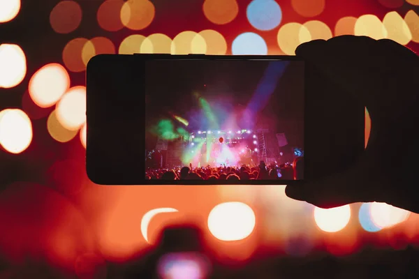 Personas que toman fotografías con un teléfono inteligente táctil durante una música — Foto de Stock