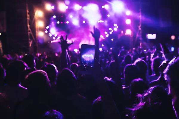 People taking photographs with touch smart phone during a music