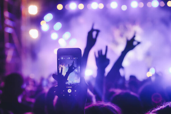 People taking photographs with touch smart phone during a music 