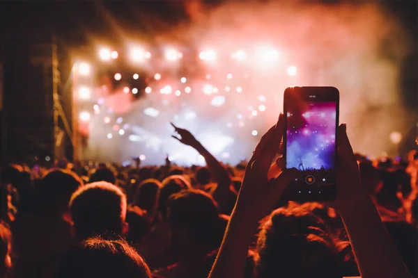 Personas que toman fotografías con un teléfono inteligente táctil durante una música — Foto de Stock