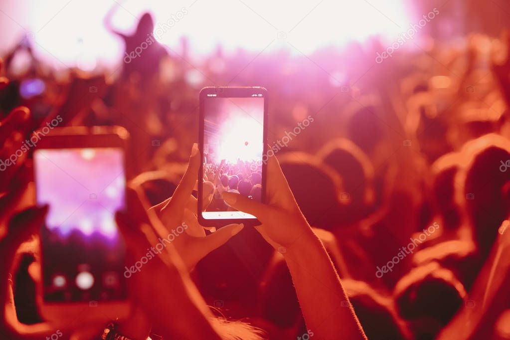 People taking photographs with touch smart phone during a music 