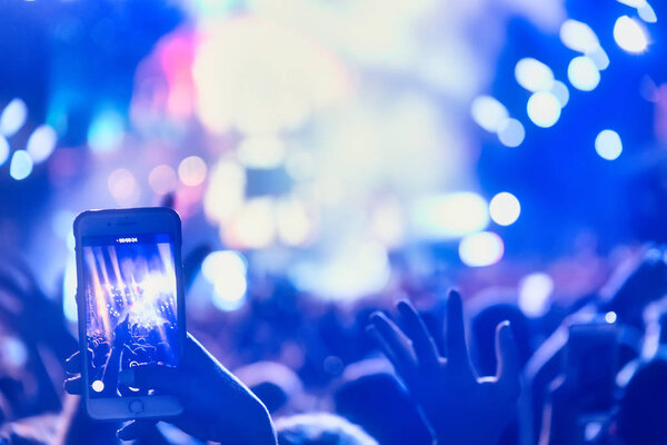 People taking photographs with touch smart phone during a music 