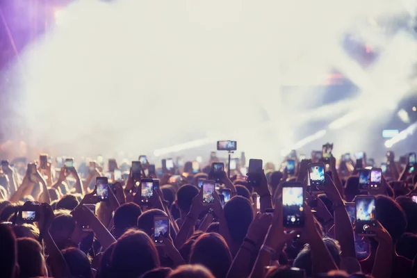 Personas que toman fotografías con un teléfono inteligente táctil durante una música — Foto de Stock