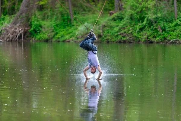 Junger Mann fliegt auf Seilrutsche über den Fluss, Extremsport — Stockfoto