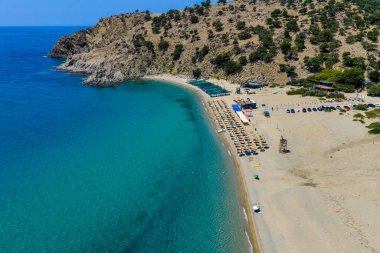 Samothraki, Yunanistan Altın kum, turkuaz deniz, kayalık tepeler ve dağınık şemsiyeleriyle Pachia Ammos Plajı 'nın havadan görünüşü