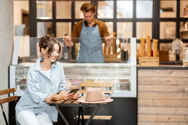 Woma en el café con un vendedor en el fondo — Foto de Stock