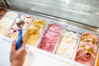 Satıcı dükkandaki buzdolabından kaşıkla dondurma topluyor.