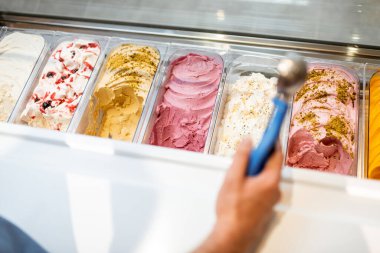 Satıcı dükkandaki buzdolabından kaşıkla dondurma topluyor.