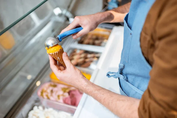 Az eladó jégkrémet szed egy kanállal a hűtőből a boltban. — Stock Fotó