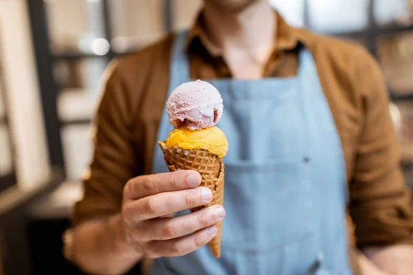 Vendedor com sorvete em um cone de waffle, close-up — Fotografia de Stock