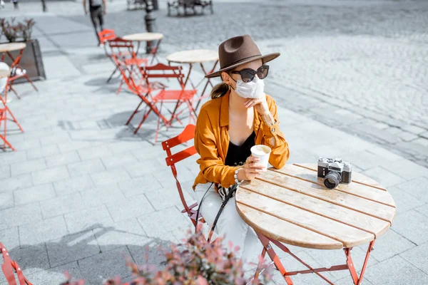Женщина в защитной маске для лица в кафе на улице — стоковое фото