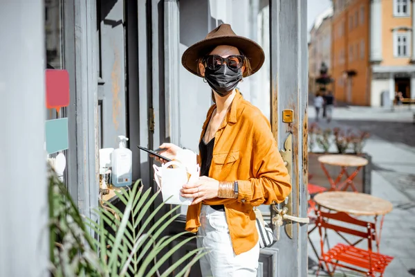 Woman in facial mask buying food and coffee at the cafe during pandemic — Stock Photo, Image