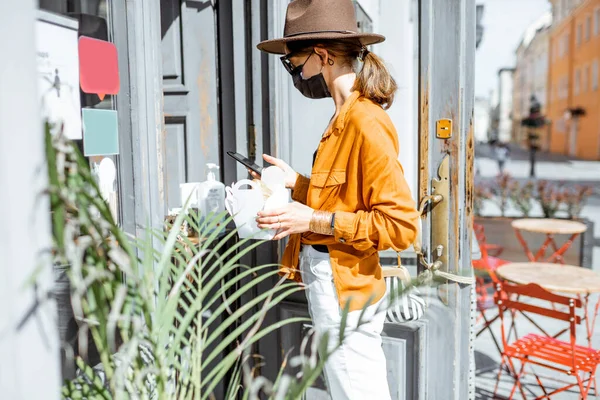 Женщина в маске покупает еду и кофе в кафе во время пандемии — стоковое фото
