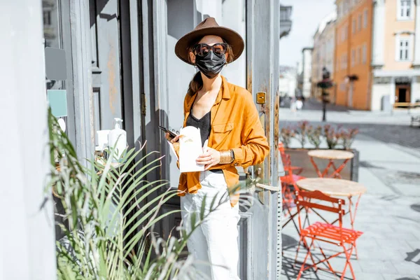 Kvinne i ansiktsmaske som kjøper mat og kaffe på kafeen under pandemien – stockfoto