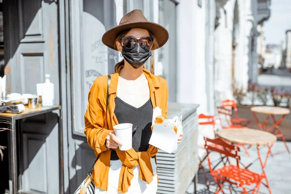 Kvinna i ansiktsmask köper mat och kaffe på caféet under pandemin — Stockfoto