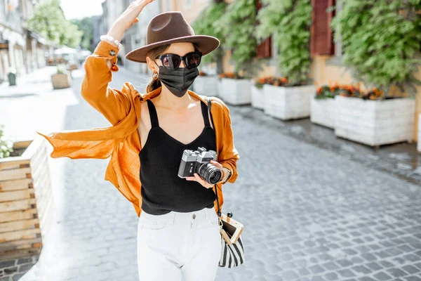 Yüz maskeli kadın eski şehirde seyahat ediyor. — Stok fotoğraf