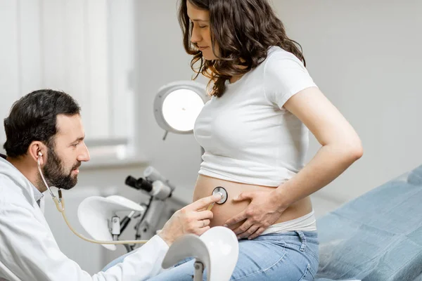 Доктор слушает беременную женщину в животе — стоковое фото