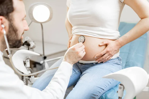 Médico ouvindo uma barriga de mulheres grávidas — Fotografia de Stock